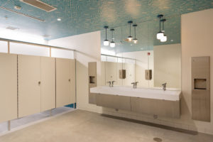 A bathroom in Detroit Public Theatre's Third Avenue Garage, where the nonprofit's logo is incorporated in a custom wallpaper on the ceiling