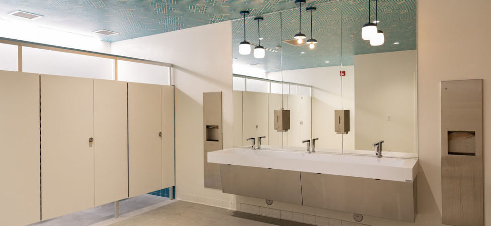 A bathroom in Detroit Public Theatre's Third Avenue Garage, where the nonprofit's logo is incorporated in a custom wallpaper on the ceiling