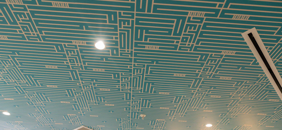 Detroit Public Theatre-branded wallpaper lines the ceiling of the bathroom at the nonprofit's Third Avenue Garage