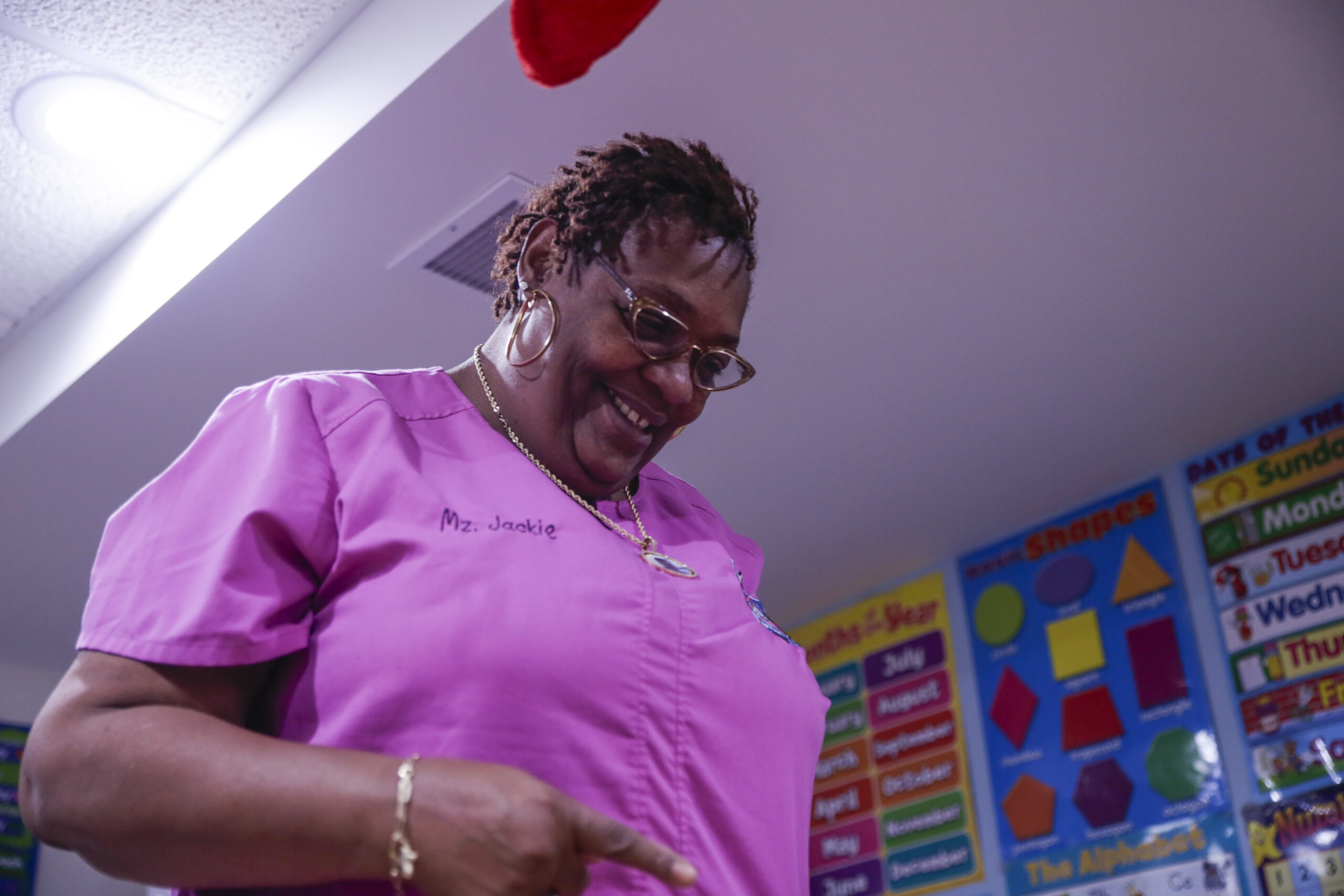 Jacqueline Hopgood-German, or Ms. Jackie, director of The Babies Club early childhood education center in south Chicago, stands smiling above a child, who is out of frame.