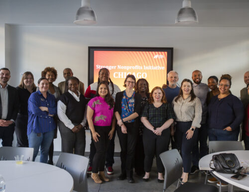 SNI Chicago cohort members pose in front of sign reading "Stronger Nonprofits Initiative Chicago"