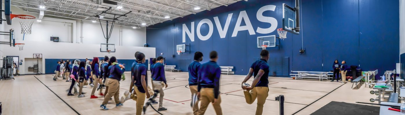 Students at the Milwaukee Academy of Science in the school's gymnasium. They are wearing uniforms consisting of dark blue tops and khaki pants, and are walking on a basketball court.