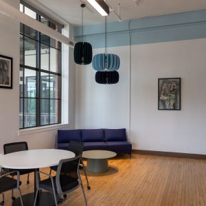Modern interior with a round table, blue sofa, pendant lights, and framed artworks.