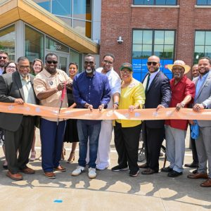 A group of people at a ribbon-cutting ceremony in front of a modern building.