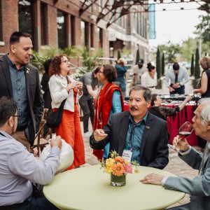 A group of people sits at a table in a covered courtyard outside