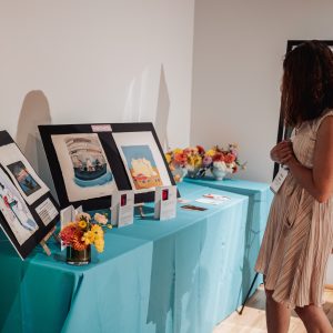 A woman looks at a table full of pictures and physical artworks