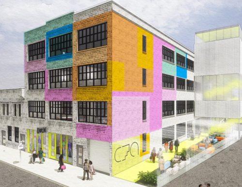 A multi-story building with colorful panels and large windows next to a modern extension with a translucent facade.