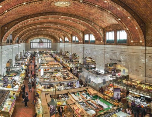 Interior of a historic market hall with arched brick ceilings and vendor stalls.