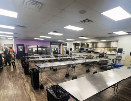 A large commercial kitchen with metal tables, trash bins, and kitchen equipment.