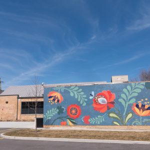 External of a single-story brick building with a mural flowers painted on one face