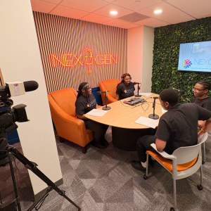 A group of young people engaged in a discussion around a table with microphones.